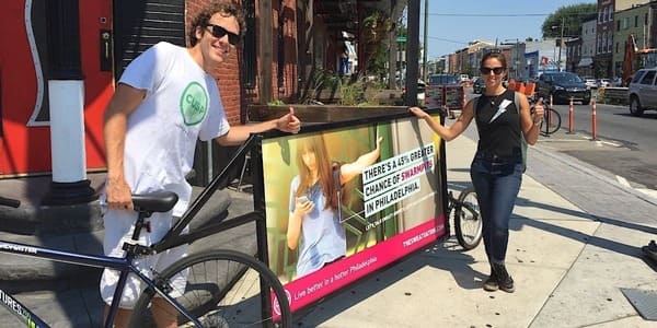 two people standing next to a bike ad

ads on bikes