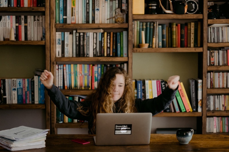 Person celebrating at their desk looking at their laptop