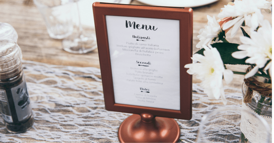 A restaurant menu stand that's been placed on a well-decorated table.