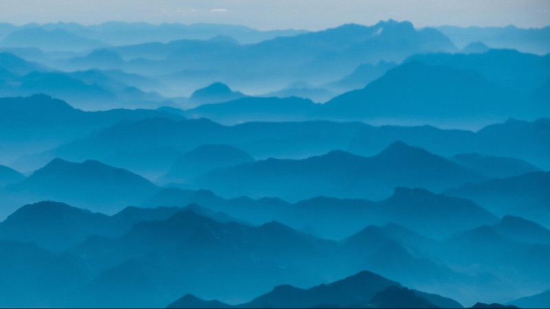 A blue monochromatic design showing a foggy mountain range